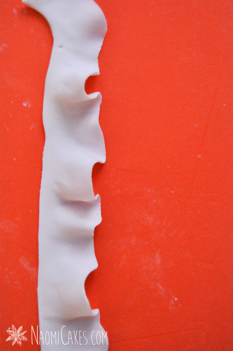 a ruffled strip of gum paste/fondant on an orange mat for making cakes