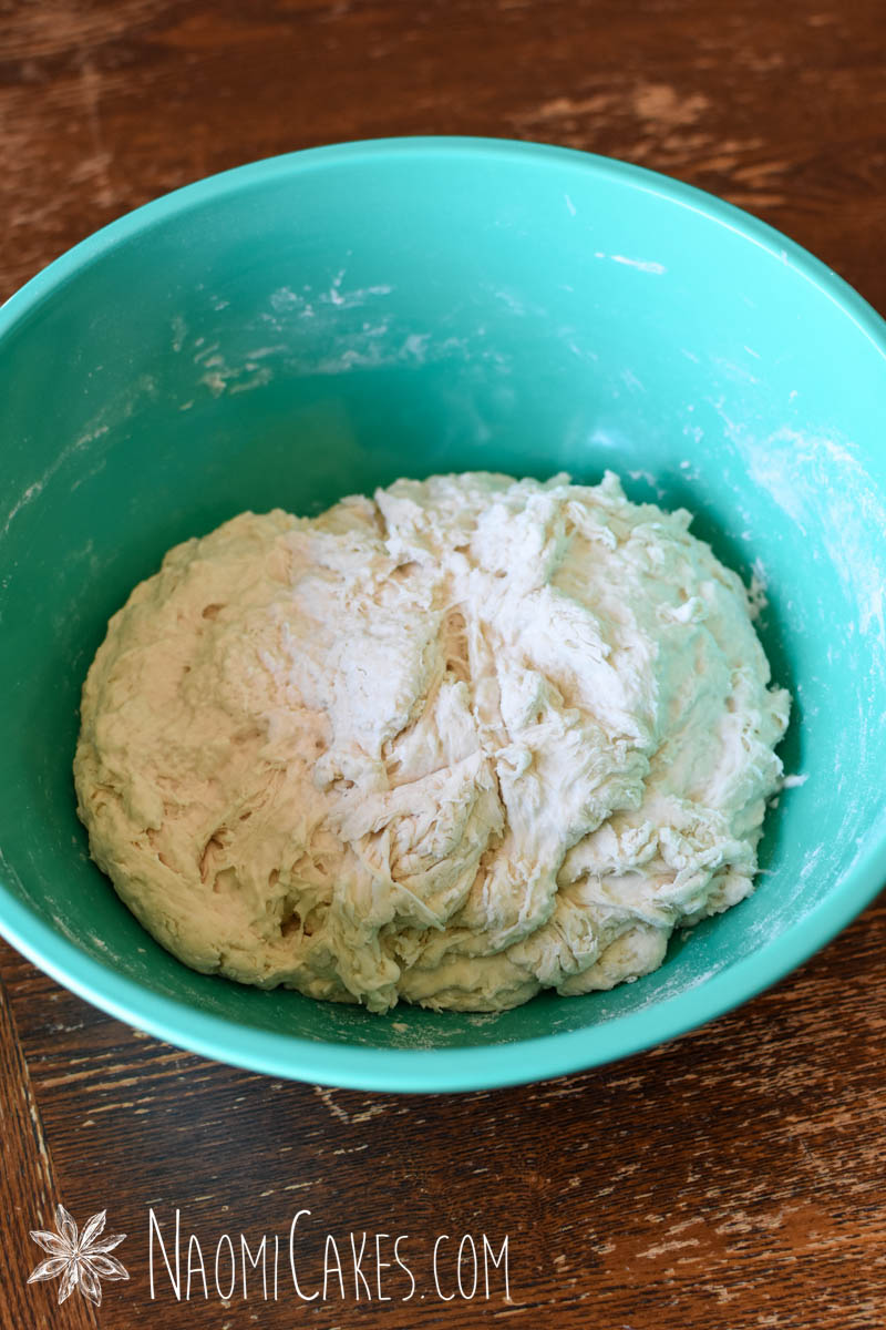 rough dough in a green bowl on a wooden table