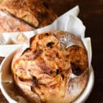 banneton basket with a loaf of cheesy sourdough bread